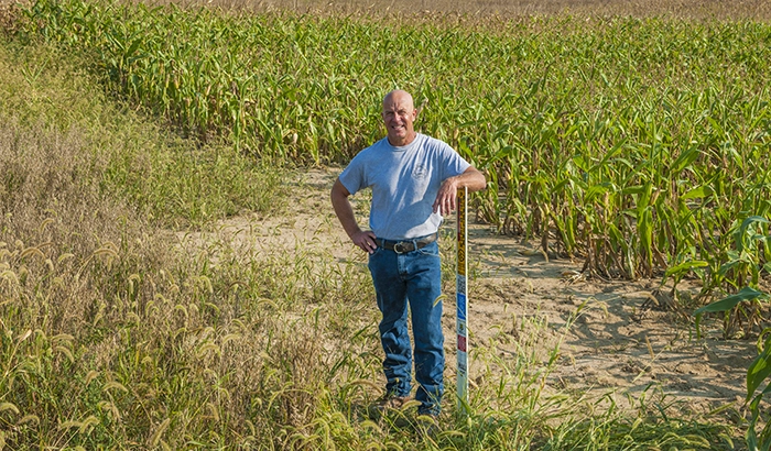 A farmer standing in a field with a smile on his face