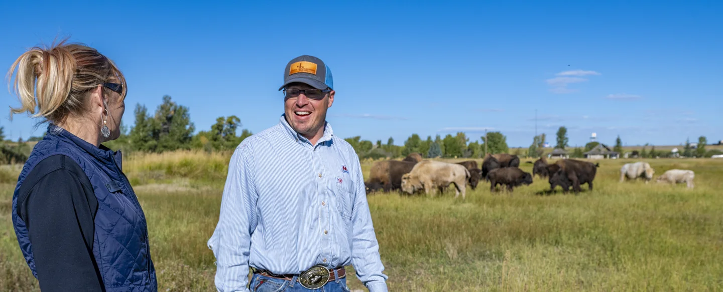 A Marathon Pipe Line employee talking to a conservationist next to a field of buffalo