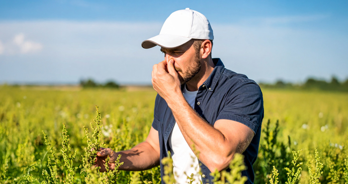 A farmer covering his nose outside from a strange odor indicating a pipeline leak