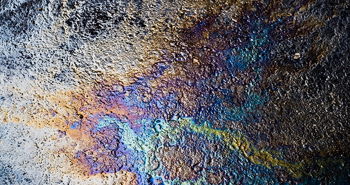 A rainbow sheen on water near a farm, indicating a potential pipeline leak