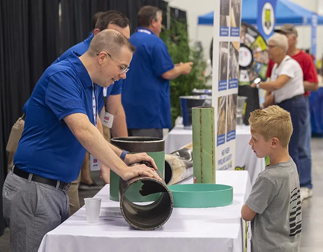 An MPL employee showing a child a piece of a pipeline at an Marathon Pipe Line booth