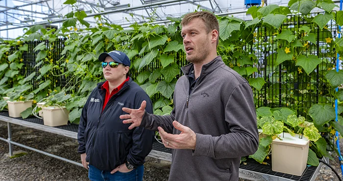 An MPL representative talking to peple in a large green house